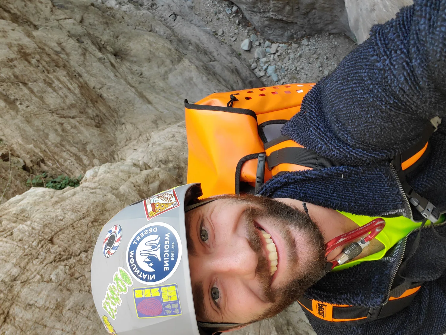 Jason Weber smiling while carrying canyon rescue equipment in a narrow stone canyon
