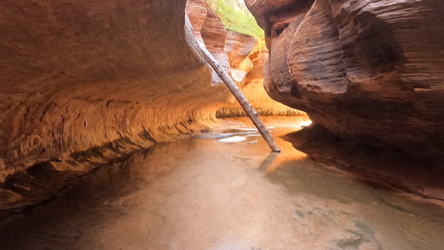 A narrow sandstone passage opening into warm reflected light